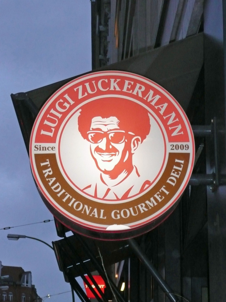 The sign for Luigi Zuckermann, a deli in Berlin, lit up at dusk