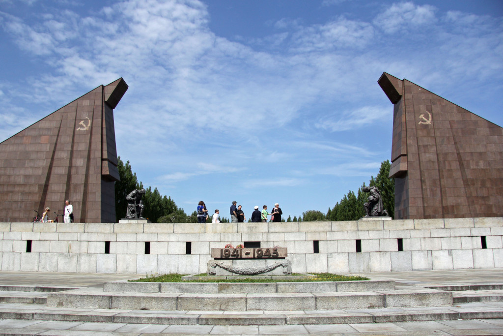 The red granite gateway and statues of kneeling soldiers at the Soviet War Memorial in Teptower Park in Berlin