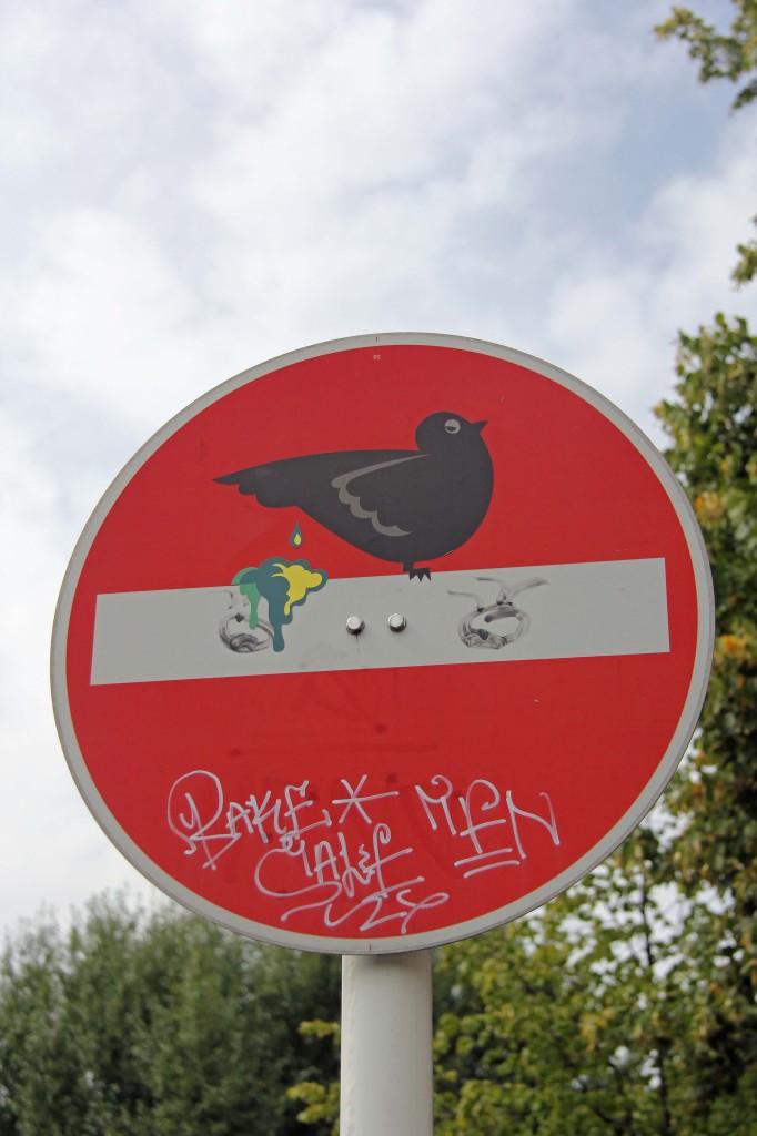 Bird Shitting On Perch: A modified street sign - Street Art by CLET in Berlin