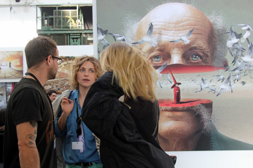 A group of visitors discuss the artwork at Stroke Urban Art Fair 2012 in Berlin