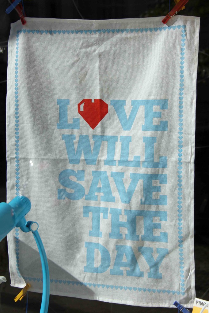 Love Will Save The Day - Tea Towel in the window of Uhranus on Kastaniallee, Berlin