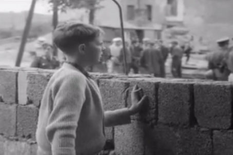 A boy stands at the Berlin Wall in 1961
