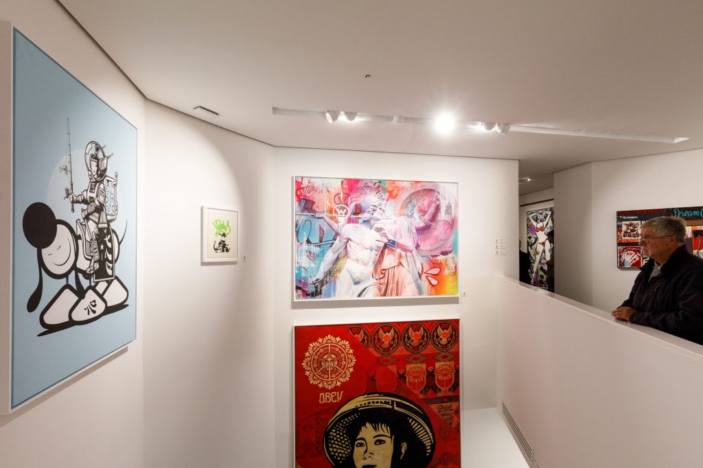Ein Besucher bewundert ein Kunstwerk von The London Police (auch zu sehen Kunstwerke von Shepard Fairey, Banksy and Pichiavo) im Urban Nation Museum for Urban Contemporary Art in Berlin